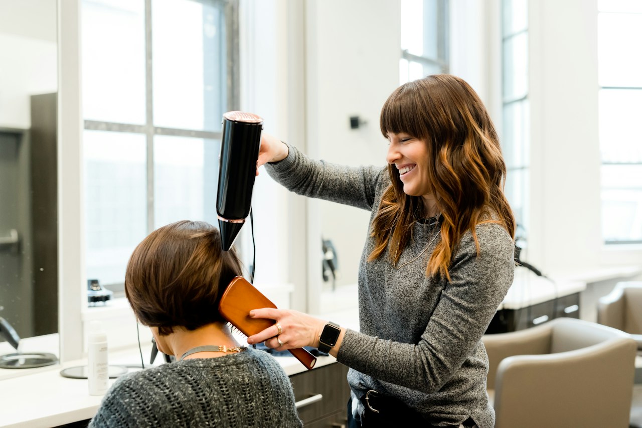 Coiffeuse réalisant un brushing dans un salon