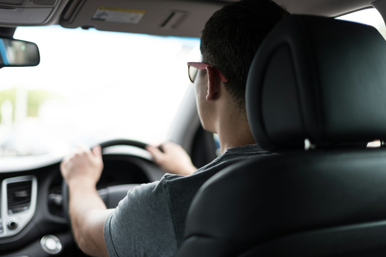 Chauffeur VTC au volant, vu depuis la banquette arrière