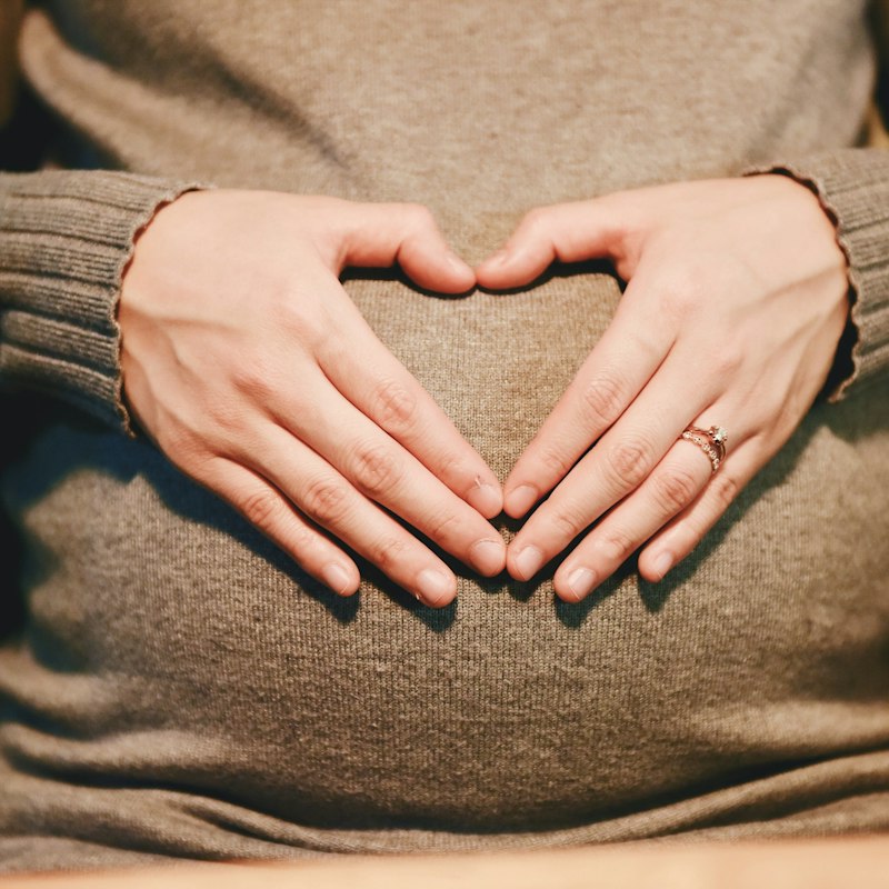 Mains formant un cœur sur un ventre de femme enceinte