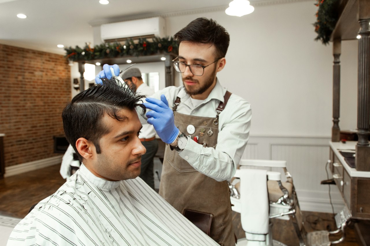 Coiffeur réalisant une coupe dans son salon