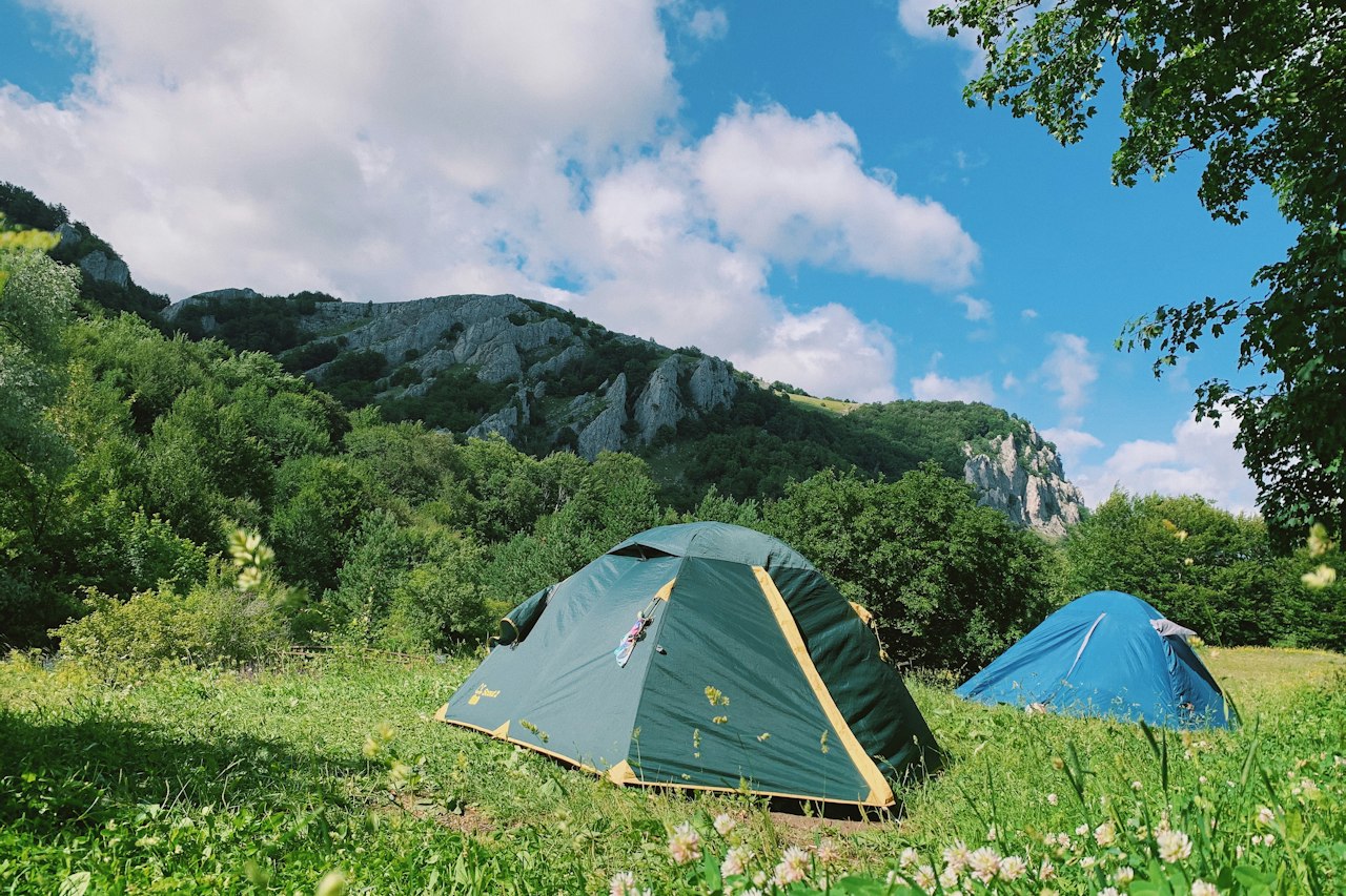 Tentes dans un pré au pied des montagnes