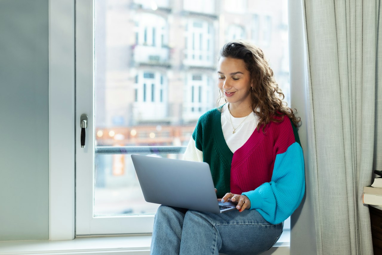 Femme travaillant sur son ordinateur portable près d'une fenêtre