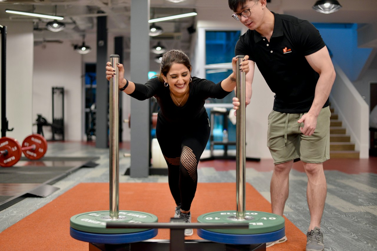 Coach sportif accompagnant une cliente pendant un exercice en salle