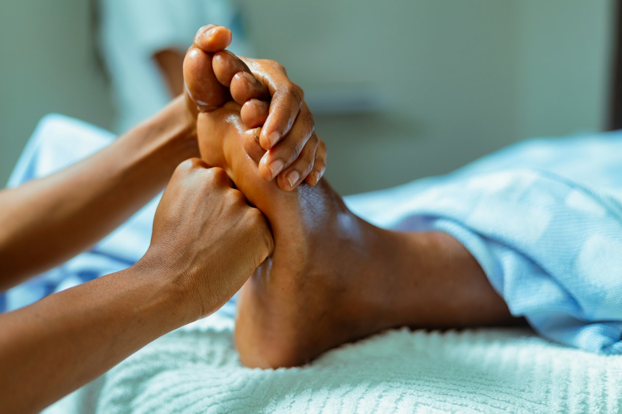 Mains d'une réflexologue sur le pied d'une personne allongée