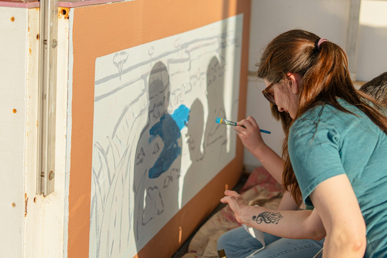 Femme peignant une fresque murale avec un pinceau