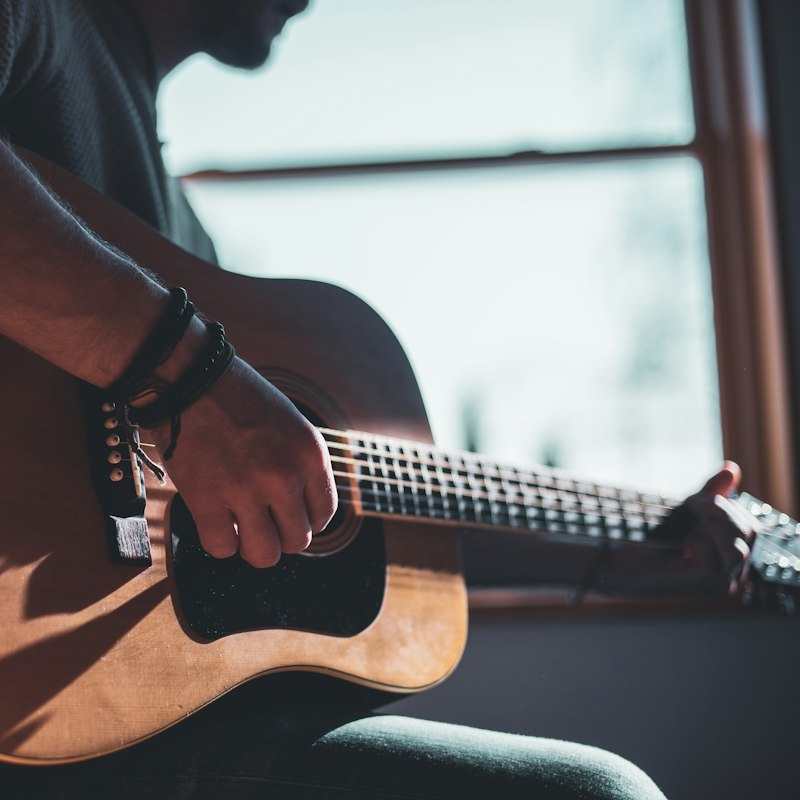 Mains jouant de la guitare acoustique