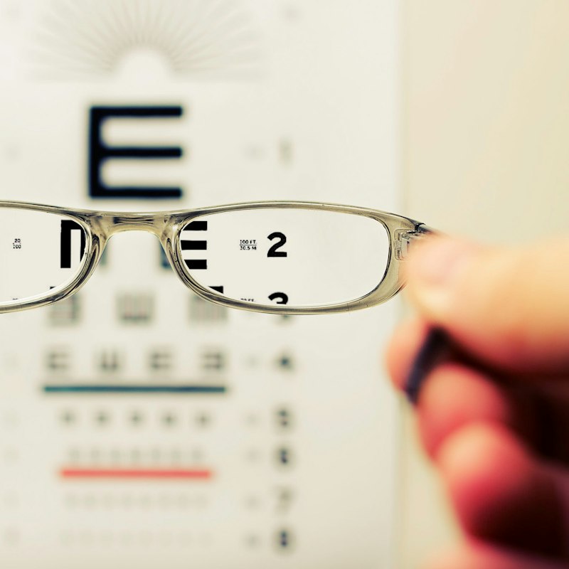 Lunettes tenues devant une échelle d'acuité visuelle