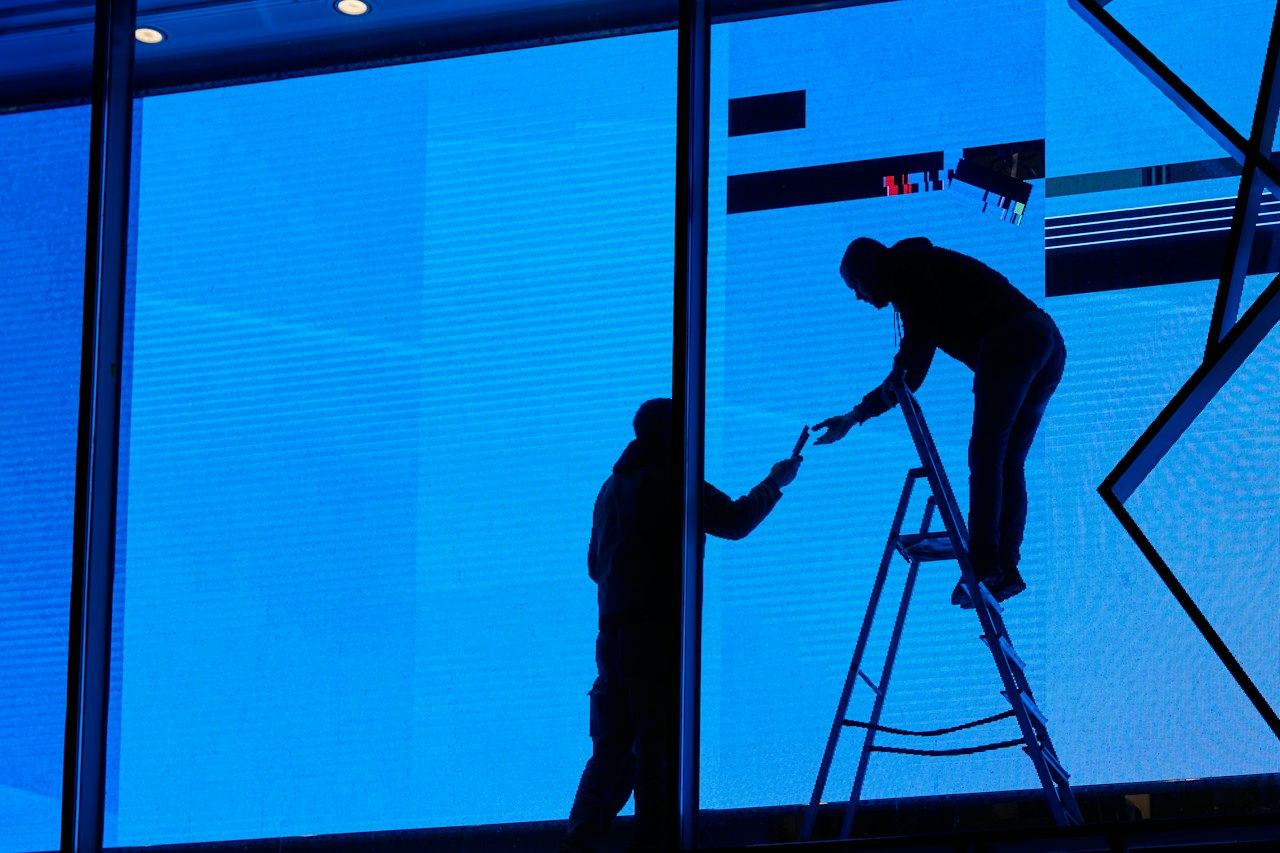 Vitrier installant un panneau de verre sur une grande baie