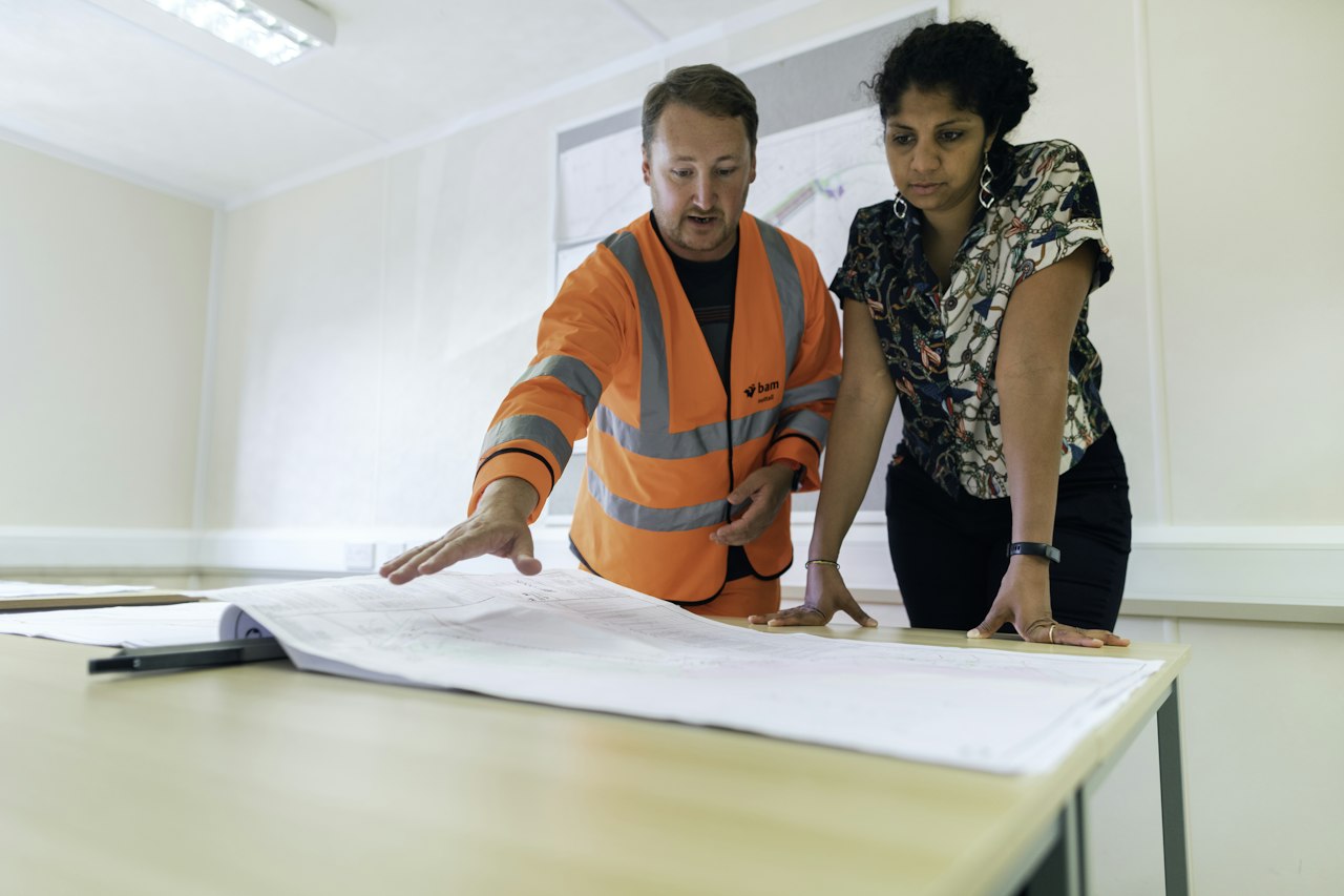 Conducteur de travaux et cliente examinant des plans sur une table
