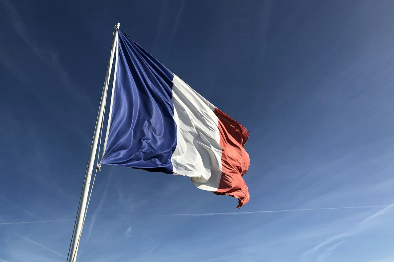 Drapeau français flottant sur un mât devant un ciel bleu