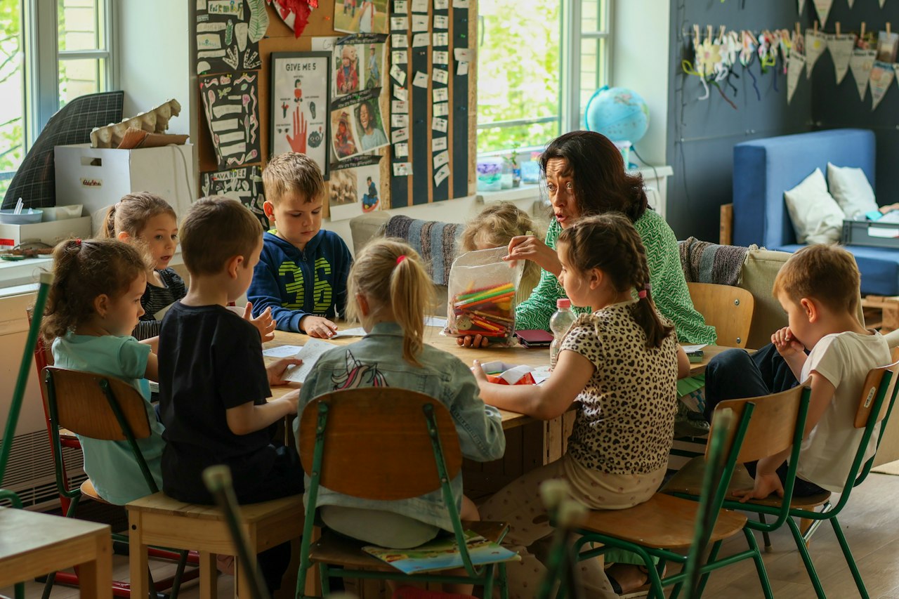 Adulte et groupe d'enfants attablés lors d'un atelier de classe
