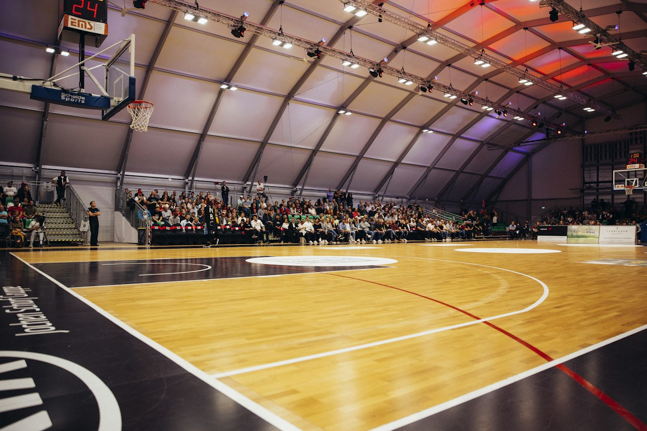 Gymnase de basket vu depuis le bord du terrain, avec ses paniers et ses gradins