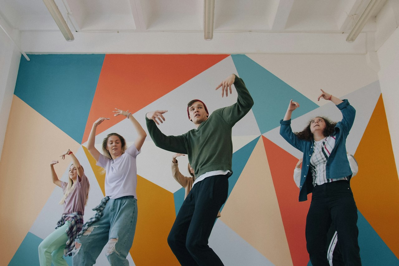 Groupe de danseurs en mouvement dans un studio devant une fresque colorée