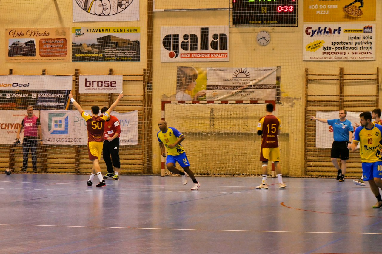 Match de handball en salle, deux équipes face à face sur un terrain de parquet