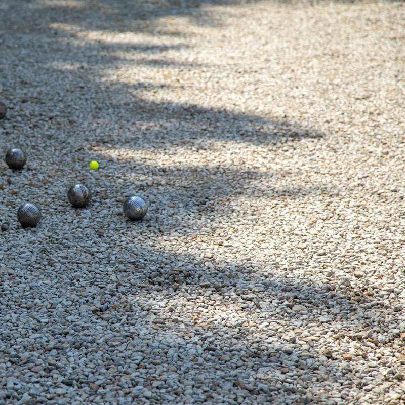 Boules en métal disposées sur le gravier d'un boulodrome
