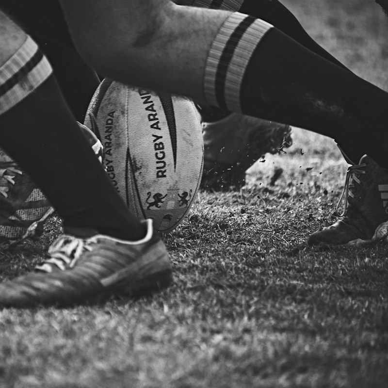 Ballon de rugby au sol et crampons de joueurs en gros plan