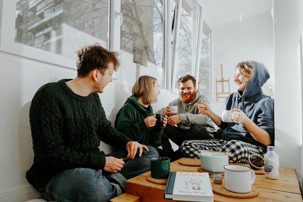 Quatre amis rient et discutent autour d'un café, l'un d'eux raconte quelque chose avec enthousiasme